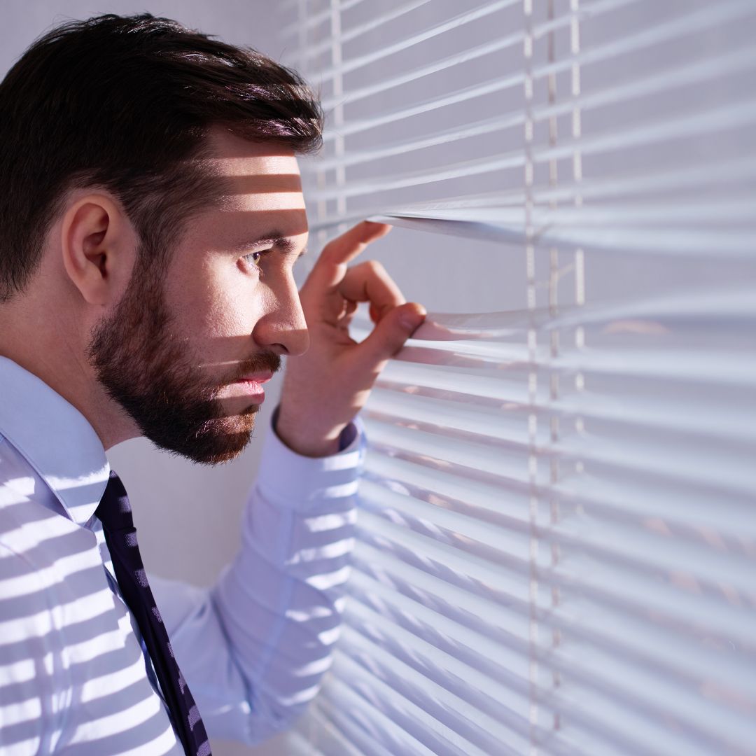 Man peering through blinds