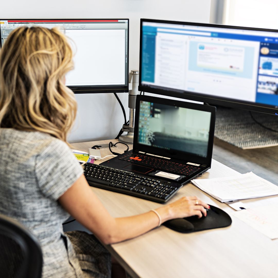 woman at her work desk on computer screens