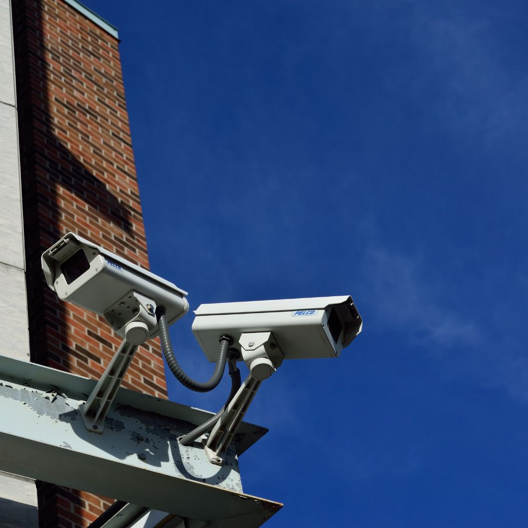 close up of two security cameras on a ledge of a corner of a building