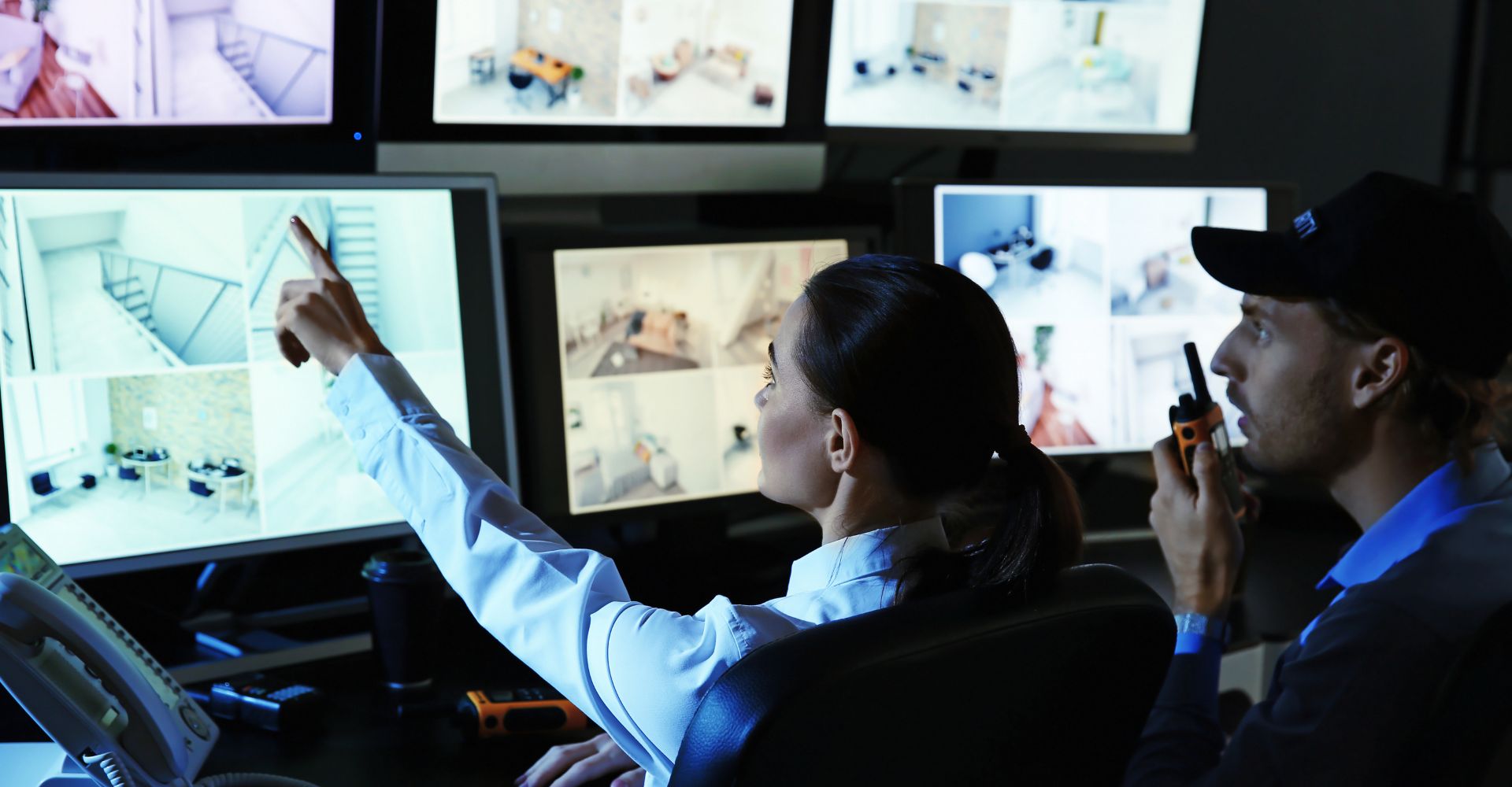 two people looking at security camera footage on multiple screens