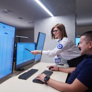Two security professionals look at screens and smile