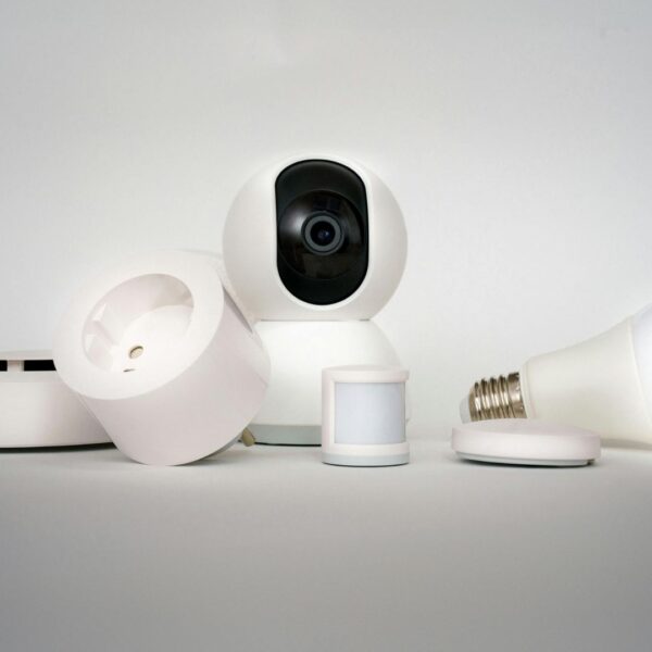 Close-up of various smart home security devices, including a keypad, a motion sensor, and a camera, neatly mounted on a white wall.